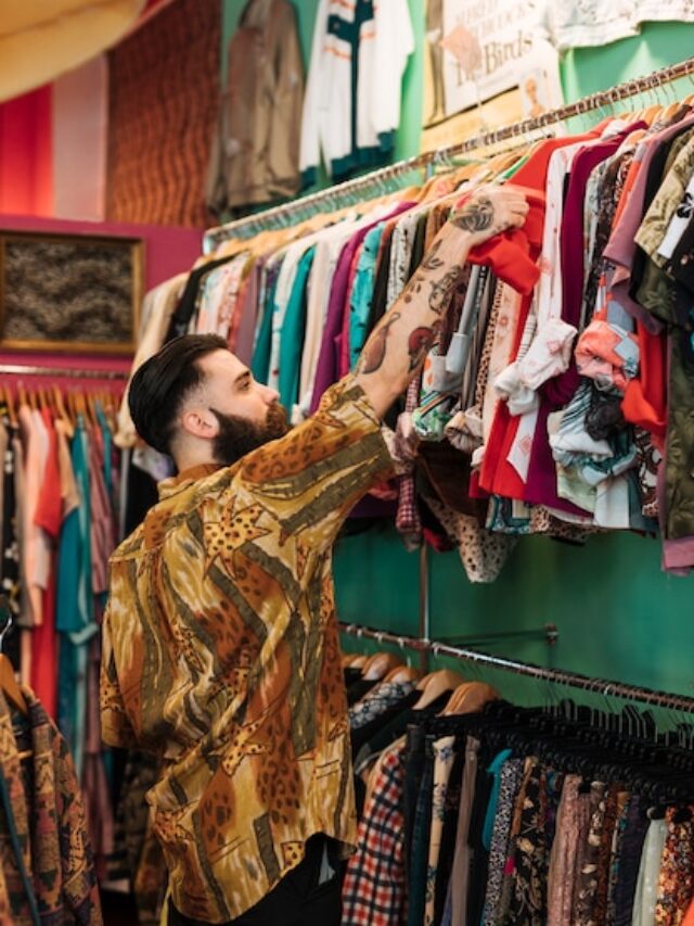 bearded-young-man-choosing-red-t-shirt-from-rail-clothing-shop_23-2148175642